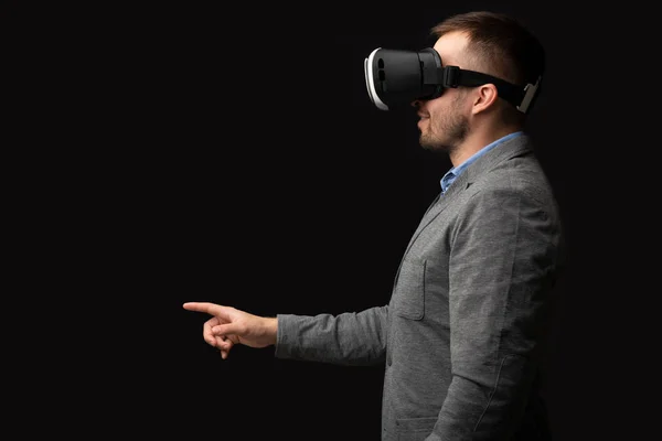 Caucasian businessman in VR headset pointing to virtual object
