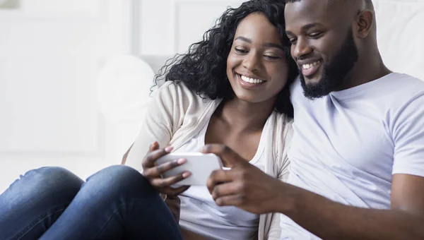 Молода пара переглядає соціальні мережі на смартфоні вдома — стокове фото