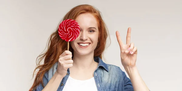 Lollipop en manos de linda chica que muestra signo de paz — Foto de Stock