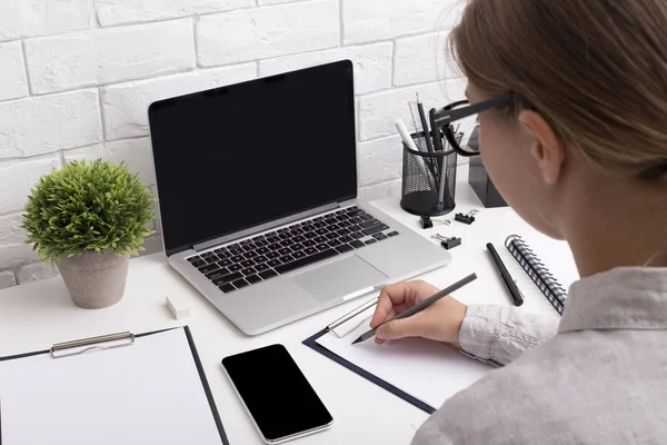 Молода дівчина офіс працівник пише завдання на день на сучасному столі — стокове фото