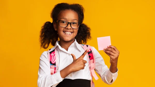 Black Elementary Student Girl Pointing At Blank Paper, Yellow Background — Stok Foto