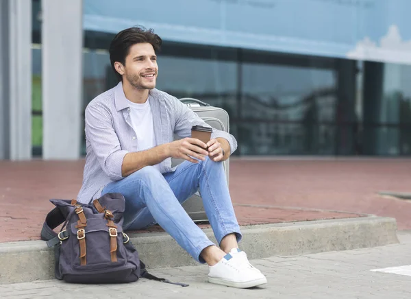 Ung manlig resenär sitter nära flygplatsterminalen med kaffe — Stockfoto