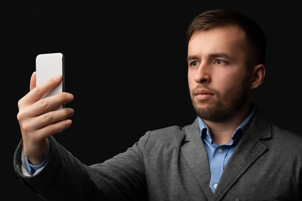 Молодий сучасний чоловік у костюмі, використовуючи розпізнавання обличчя на смартфоні — стокове фото