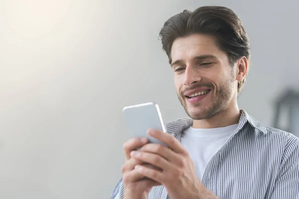 Alegre hombre milenario mensajes de texto con un amigo en el teléfono celular —  Fotos de Stock