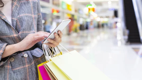 Shopping tid. Oigenkännlig kvinna med mobiltelefon och inköp — Stockfoto