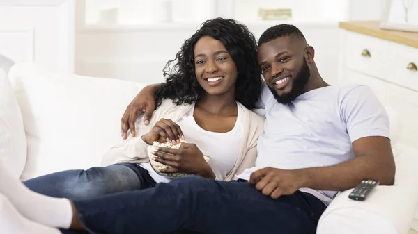 Afro casal assistindo tv, sentado com pipocas em casa — Fotografia de Stock