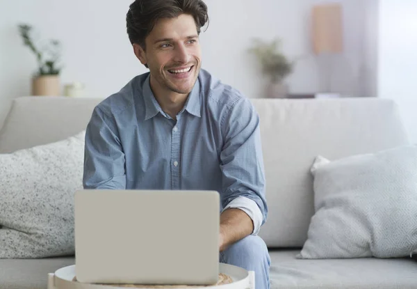 Homem usando laptop fazendo chamada de vídeo sentado no sofá — Fotografia de Stock