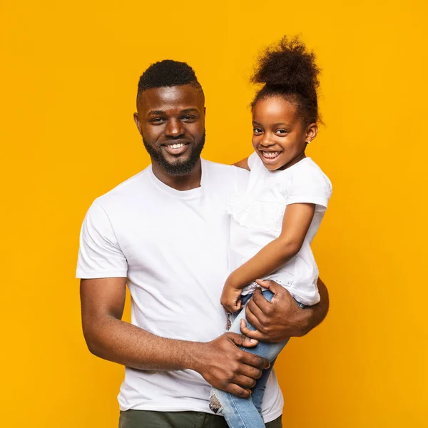 Cheerful african dad holding his cute little daughter on hands — Stock Photo, Image