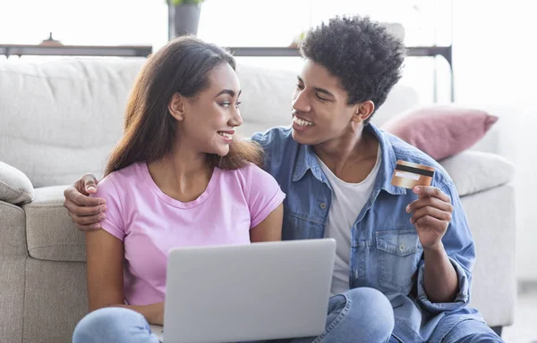 Jong Afrikaans koppel online winkelen, met behulp van laptop en creditcard — Stockfoto