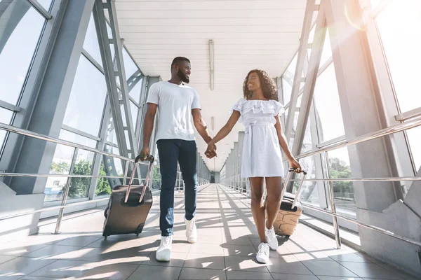 Viajeros negros activos caminando con equipaje en el aeropuerto — Foto de Stock