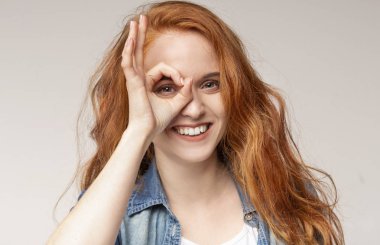 Ok işareti gösteren oynak kızıl saçlı kız, parmakları ile gesturing