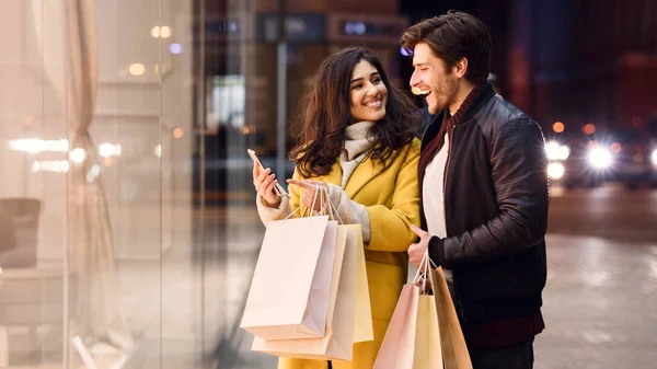 Jovem casal com sacos de compras e smartphone perto do shopping — Fotografia de Stock