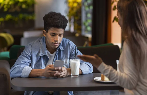 无聊的黑人家伙看着智能手机在约会时间 — 图库照片