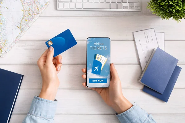 Жінка тримає кредитну картку і смартфон, купуючи квитки на літак онлайн — стокове фото