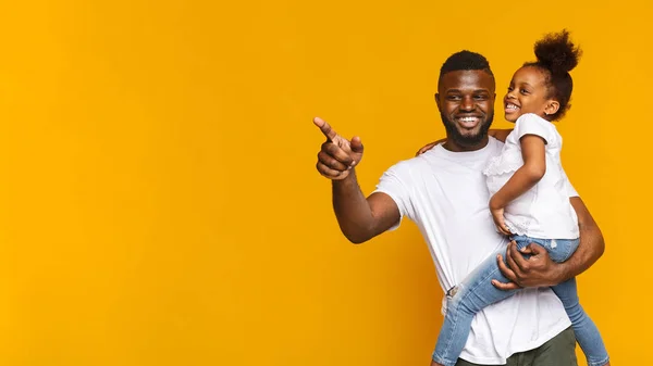 Vrolijke Afrikaanse man die iets aan zijn kleine dochter toont — Stockfoto