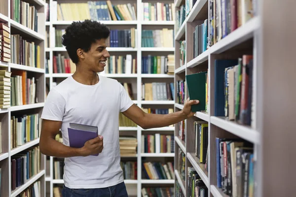 Csinos fekete srác keres könyvet könyvespolcok könyvtár — Stock Fotó