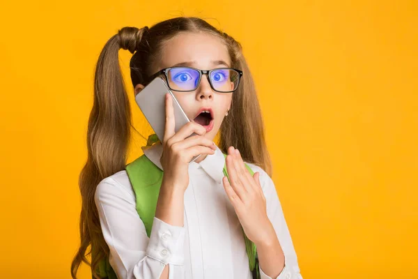 Geschokt elementaire student meisje praten op telefoon in Studio — Stockfoto