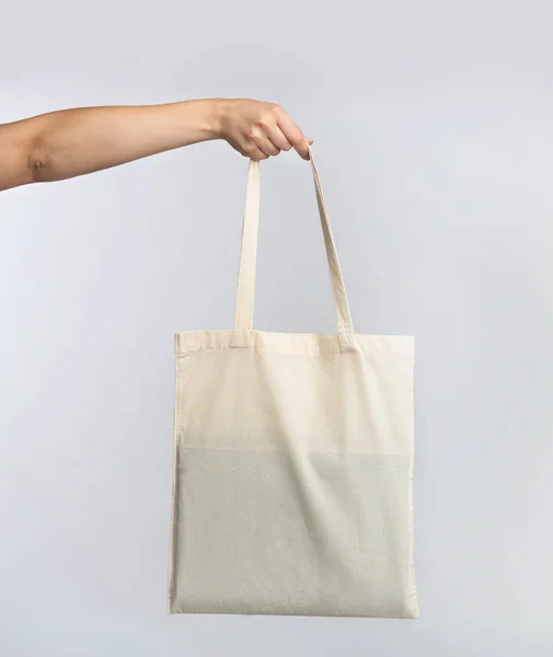 Mano sosteniendo blanco en blanco Eco Bag sobre fondo del estudio — Foto de Stock