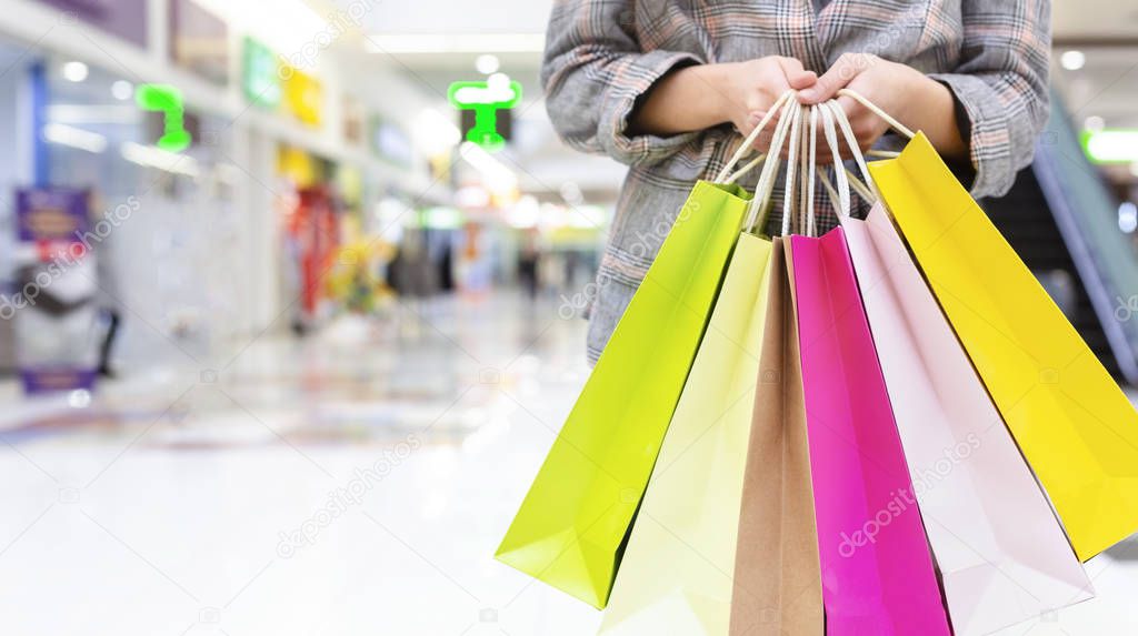 Woman shopaholic holding colourful shopping bags, copy space