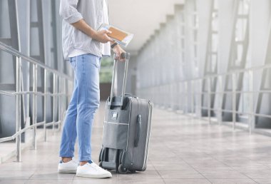 Bagaj ve biniş belgeleri ile erkek turist uçuş bekliyor