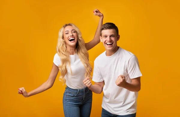 Jovem casal alegre levantando as mãos em espanto feliz — Fotografia de Stock