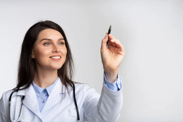 Doctor sosteniendo lápiz óptico dibujando en pantalla invisible, fondo blanco —  Fotos de Stock