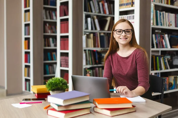 若い女性科学者がカメラに微笑み、図書館で勉強 — ストック写真