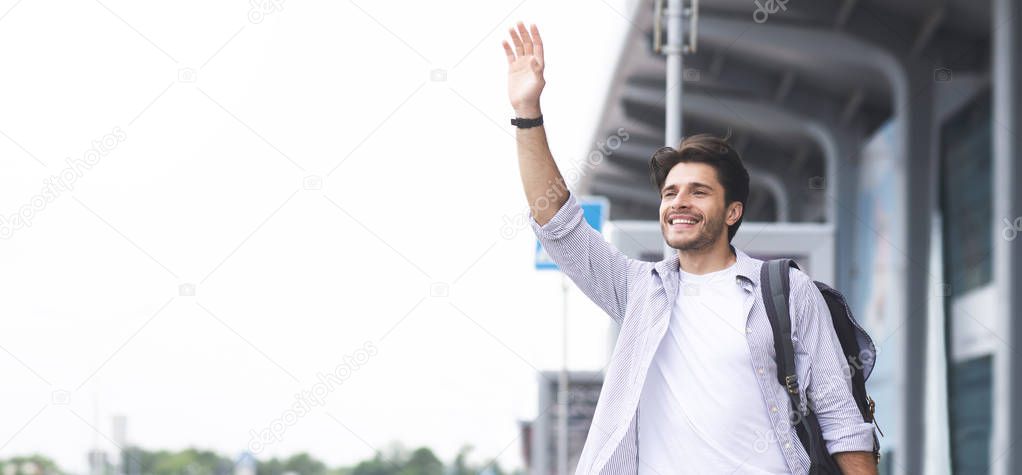 Young man waving hand near airport building, panorama