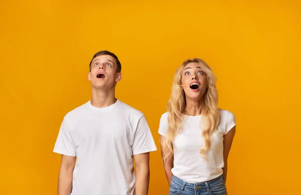 Surpreendido casal de jovens olhando para cima em excitação — Fotografia de Stock