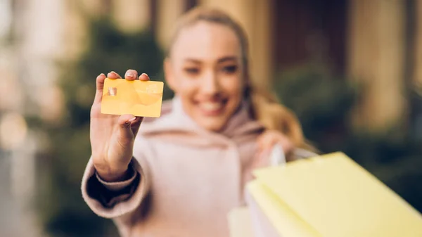 Makkelijk te betalen. Vrouw tonen creditcard, het houden van boodschappentassen — Stockfoto