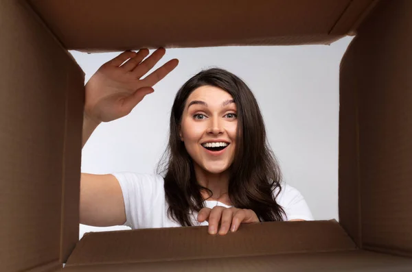 Mulher feliz olhando para dentro da caixa de papelão, vista inferior — Fotografia de Stock