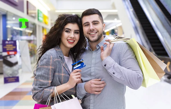 Χαμογελαστός ζευγάρι με πιστωτικές κάρτες και σακούλες για ψώνια — Φωτογραφία Αρχείου