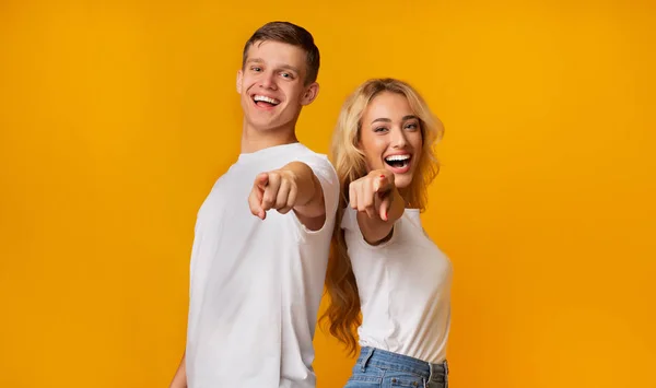 Cheerful young guy and girl pointing fingers at camera — Stock Photo, Image