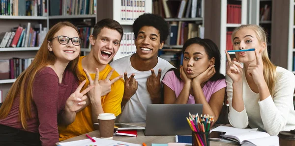 Grupo engraçado de estudantes posando na câmera na biblioteca — Fotografia de Stock