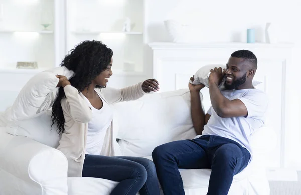 Lekfull svart par slåss med kuddar, ha kul hemma — Stockfoto