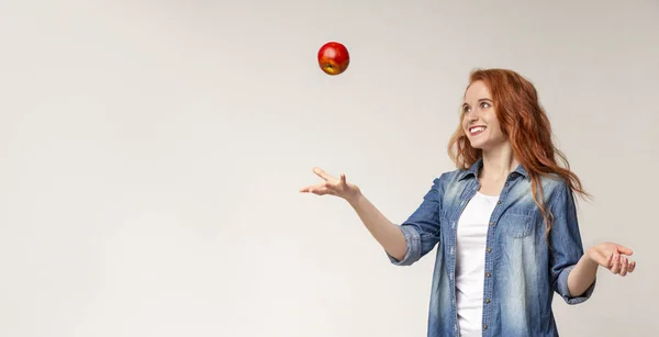 Schöne rothaarige Mädchen werfen Apfel in die Luft — Stockfoto