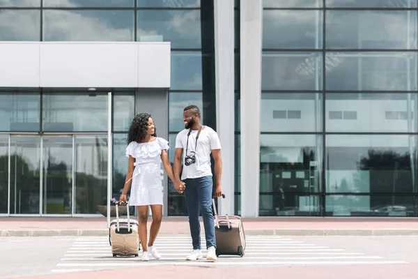 Чорна пара виходить з будівлі аеропорту з багажем — стокове фото