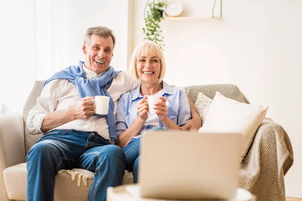 Volwassen paar kijken naar film op laptop en koffie drinken — Stockfoto