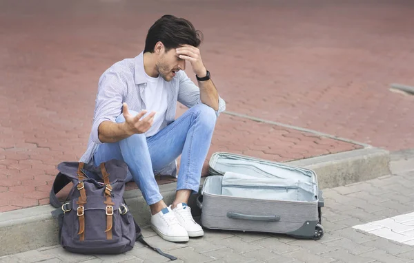 Triste hombre sentado en el aeropuerto internacional con equipaje —  Fotos de Stock