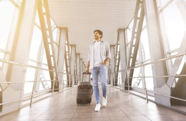 Genç bin yıllık adam havaalanında bavul ile yürüyüş