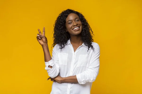Vrolijk Afro meisje demonstreert v-teken en glimlachend — Stockfoto
