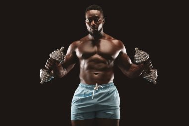 Sporcu iki eliyle çekiç bukleler yapıyor, halter kullanıyor