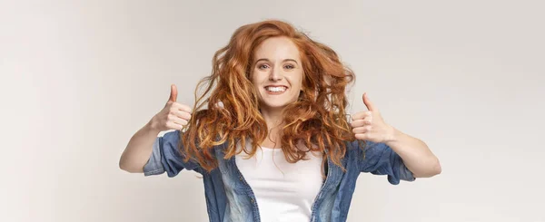 Neşeli kızıl saçlı genç eğleniyor ve başparmak gösteren — Stok fotoğraf