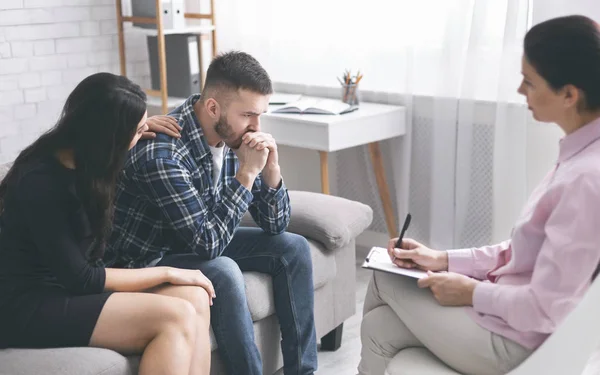 Caring wife comforting her stressed husband at psychological session — Stock Photo, Image