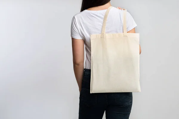 Chica sosteniendo Eco bolsa de pie detrás de la cámara en blanco — Foto de Stock