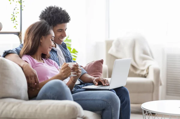 Lyckligt par sitter på soffan tittar på film på laptop — Stockfoto