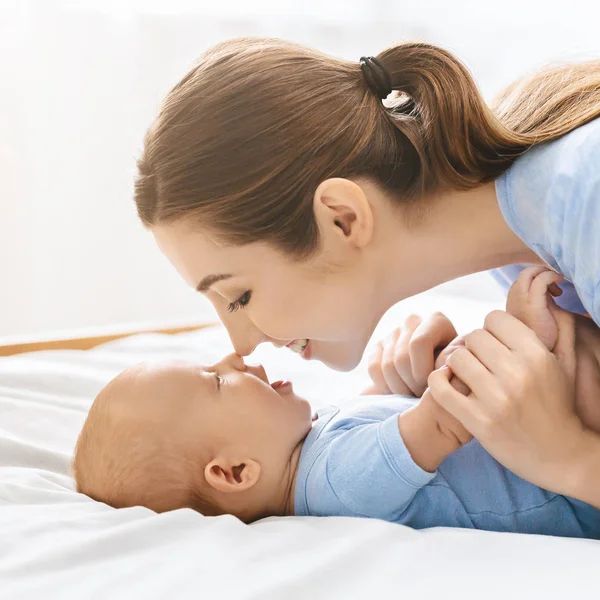 Anne ve bebek yatakta burunlara dokunuyor, birlikte eğleniyor — Stok fotoğraf