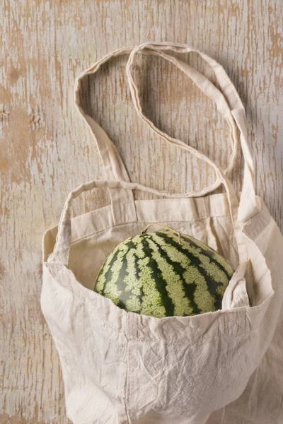 Farm watermelon in koton eco bag on wooden background