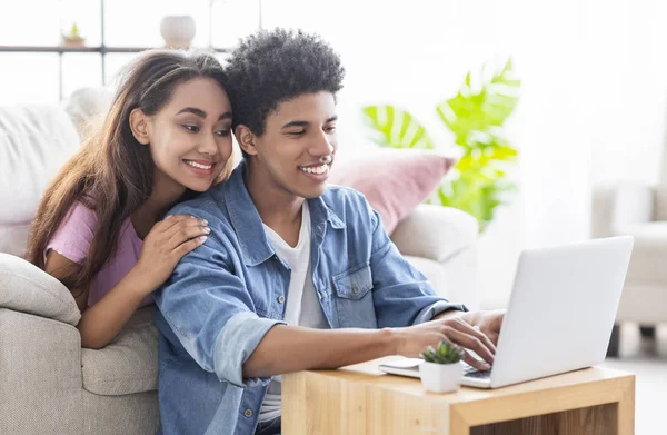 Feliz casal adolescente africano trabalhando juntos no laptop em casa . — Fotografia de Stock