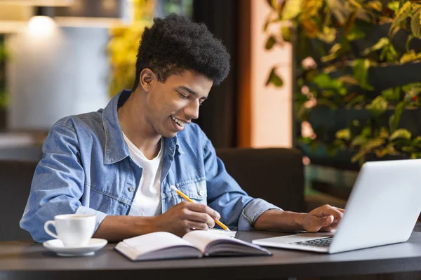 Estudiante africano exitoso trabajando en proyecto en cafetería —  Fotos de Stock